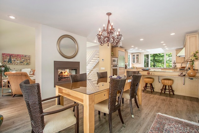 dining room with a multi sided fireplace, a notable chandelier, and light hardwood / wood-style floors