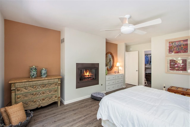 bedroom featuring ceiling fan, a closet, a spacious closet, and hardwood / wood-style flooring