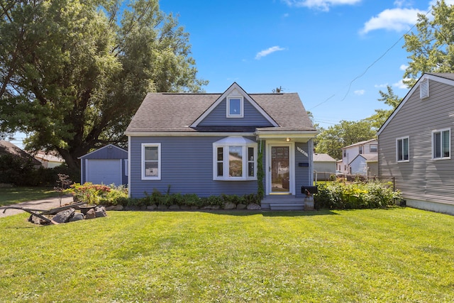 bungalow featuring a garage, a front lawn, and an outbuilding