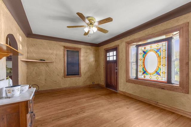 entryway featuring ceiling fan, a wealth of natural light, ornamental molding, and light hardwood / wood-style flooring