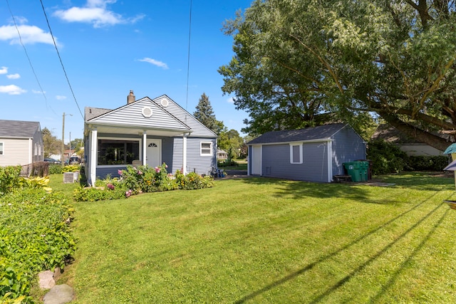 rear view of property featuring a yard and an outbuilding