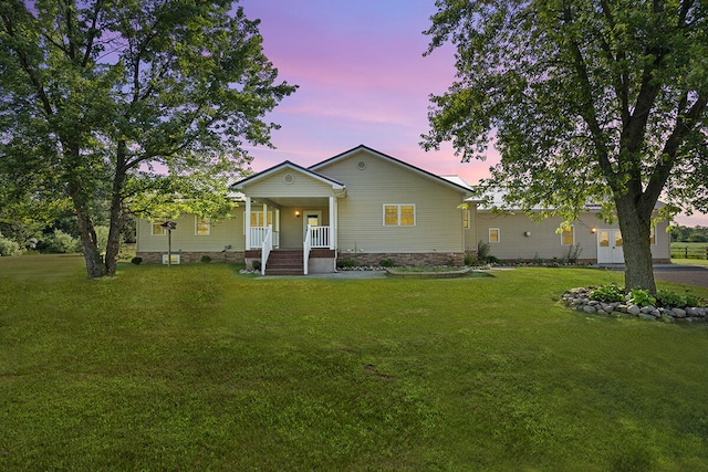 back house at dusk with a yard and covered porch