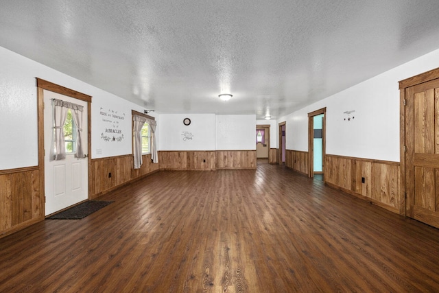 spare room with a textured ceiling, wood walls, and dark hardwood / wood-style flooring