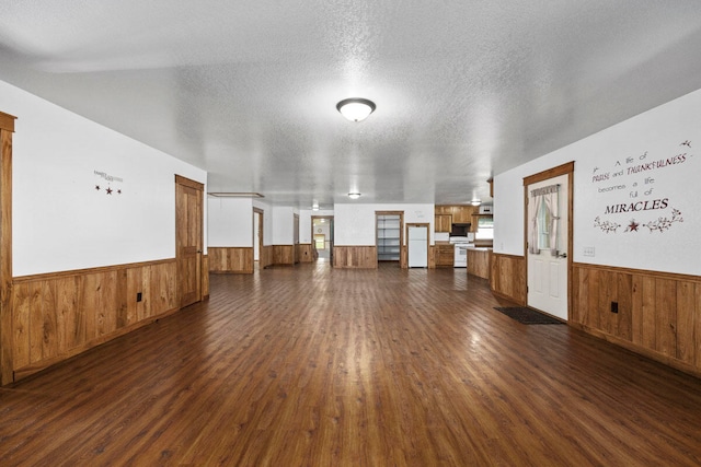 spare room with wood walls, dark hardwood / wood-style flooring, and a textured ceiling