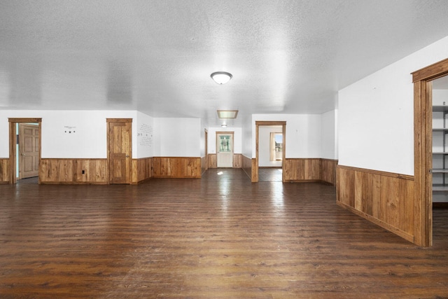 unfurnished room featuring wooden walls, dark hardwood / wood-style flooring, and a textured ceiling