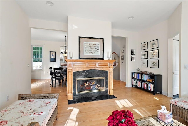 living room with a high end fireplace and light wood-type flooring