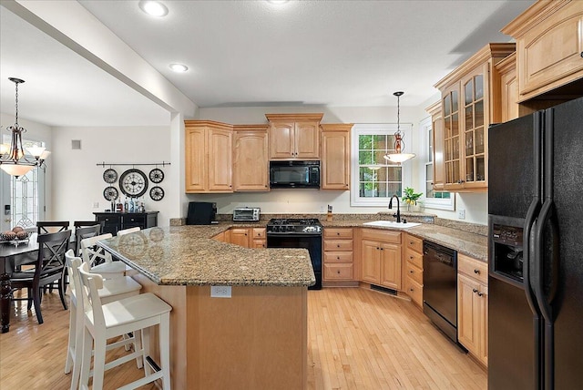 kitchen featuring light hardwood / wood-style flooring, black appliances, an inviting chandelier, and sink