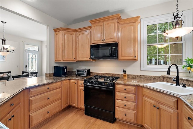 kitchen featuring stone counters, light hardwood / wood-style flooring, decorative light fixtures, black appliances, and sink