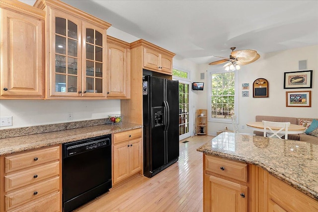 kitchen with light wood-type flooring, black appliances, light stone counters, ceiling fan, and light brown cabinets