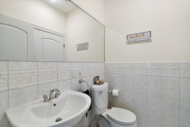 bathroom featuring tile walls, toilet, sink, and tasteful backsplash