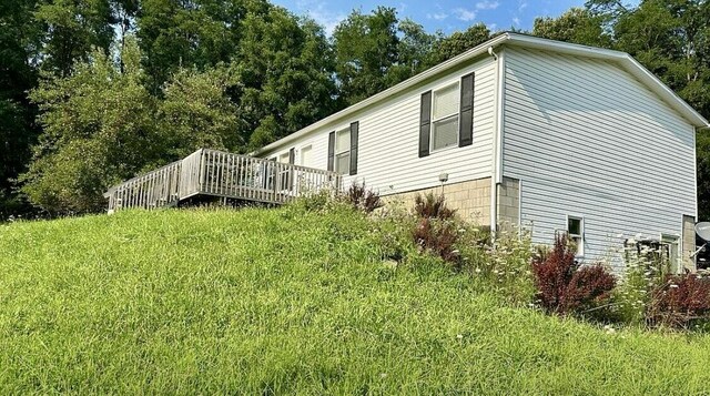 view of home's exterior with a wooden deck and a lawn