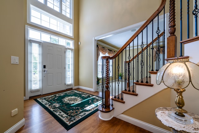 foyer entrance with a wealth of natural light, wood-type flooring, and a high ceiling