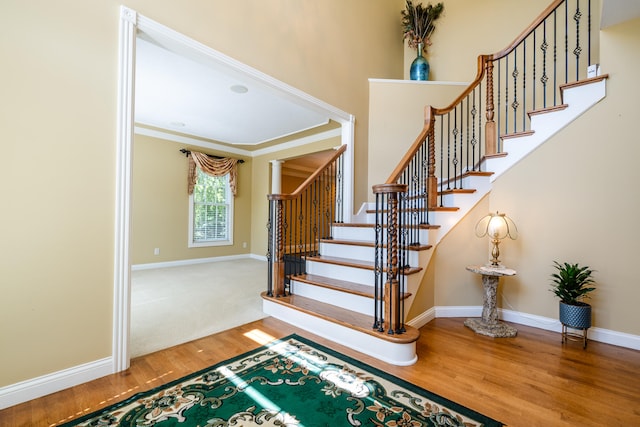 staircase with crown molding and hardwood / wood-style flooring