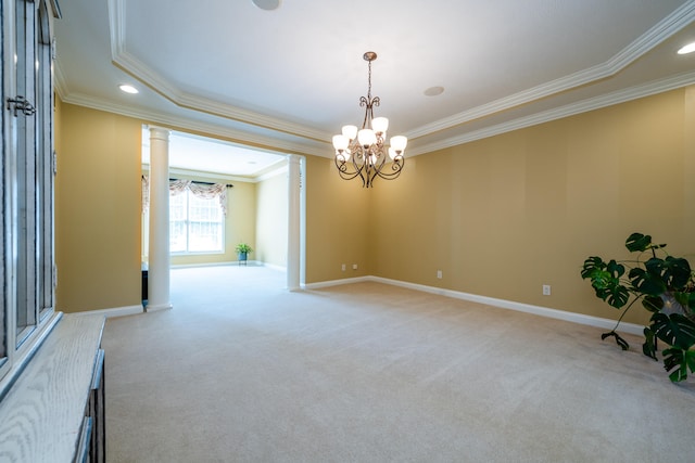 carpeted empty room with crown molding, an inviting chandelier, and decorative columns