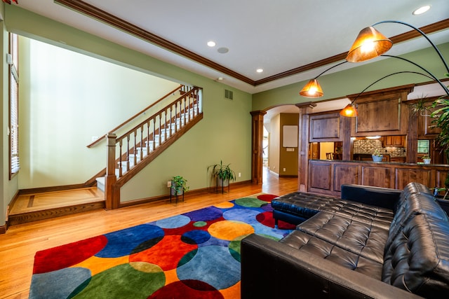 living room featuring decorative columns, light hardwood / wood-style floors, and ornamental molding