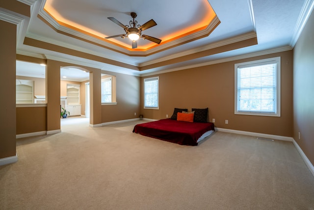 carpeted bedroom with multiple windows, a tray ceiling, and crown molding