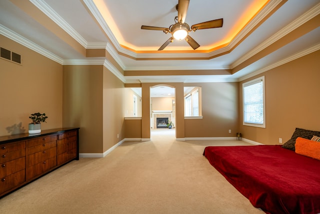 bedroom featuring light carpet, a tray ceiling, crown molding, and ceiling fan