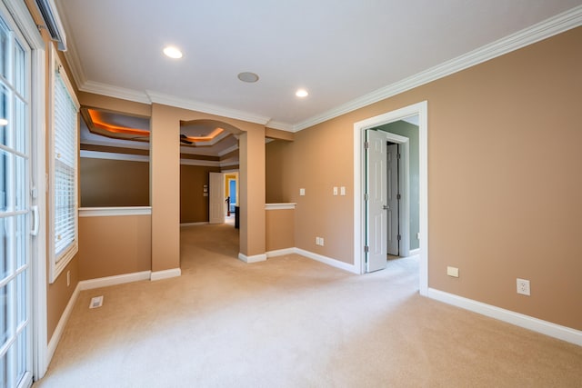 unfurnished room with ornamental molding, plenty of natural light, a tray ceiling, and light colored carpet