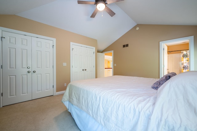 bedroom with multiple closets, vaulted ceiling, light colored carpet, and ceiling fan