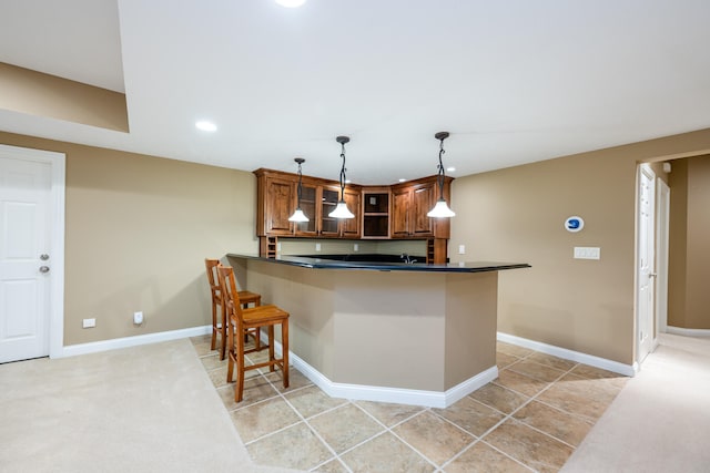 kitchen featuring light tile patterned flooring, hanging light fixtures, kitchen peninsula, and a breakfast bar