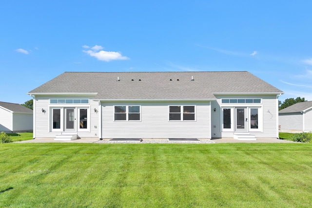 back of property with a yard, a shingled roof, and entry steps