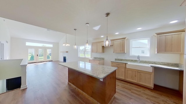 kitchen featuring light brown cabinets, open floor plan, light wood finished floors, and a sink