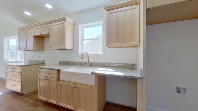 kitchen with light stone counters, recessed lighting, light brown cabinets, and a sink