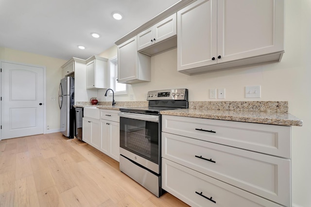 kitchen featuring light stone counters, appliances with stainless steel finishes, white cabinetry, and light hardwood / wood-style floors