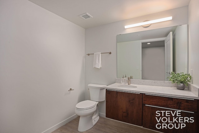 bathroom featuring toilet, hardwood / wood-style flooring, and vanity