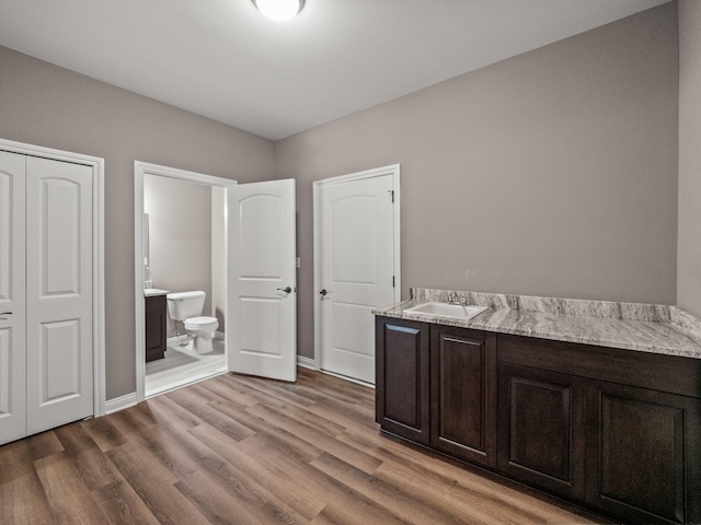 bathroom with baseboards, toilet, wood finished floors, and vanity