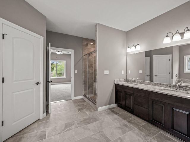 bathroom with a shower stall, double vanity, baseboards, and a sink