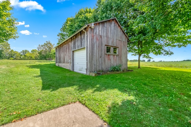 view of outbuilding featuring a garage, a lawn, and a rural view