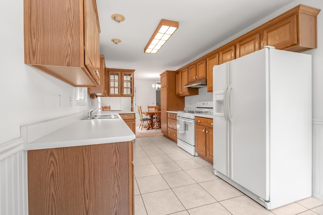 kitchen with white appliances, light tile patterned floors, and sink