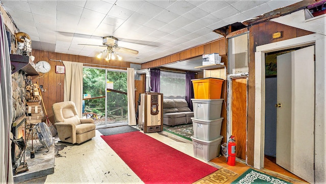 interior space with ceiling fan and wooden walls