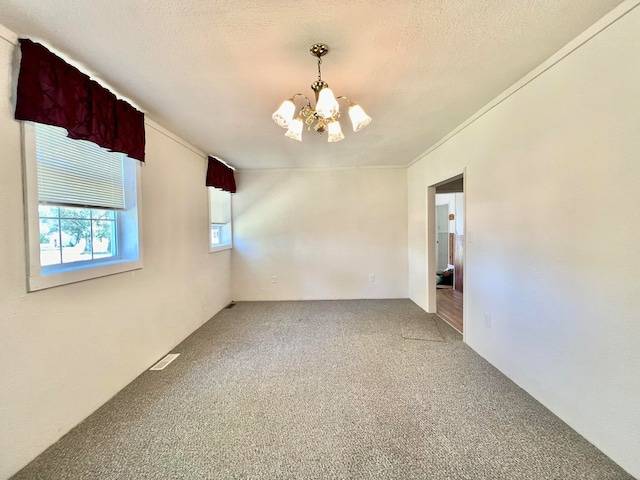 carpeted spare room featuring a textured ceiling and a chandelier