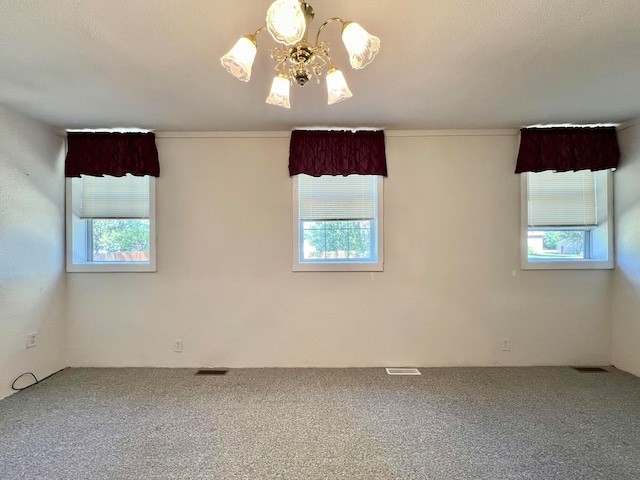 carpeted spare room with a healthy amount of sunlight and a notable chandelier