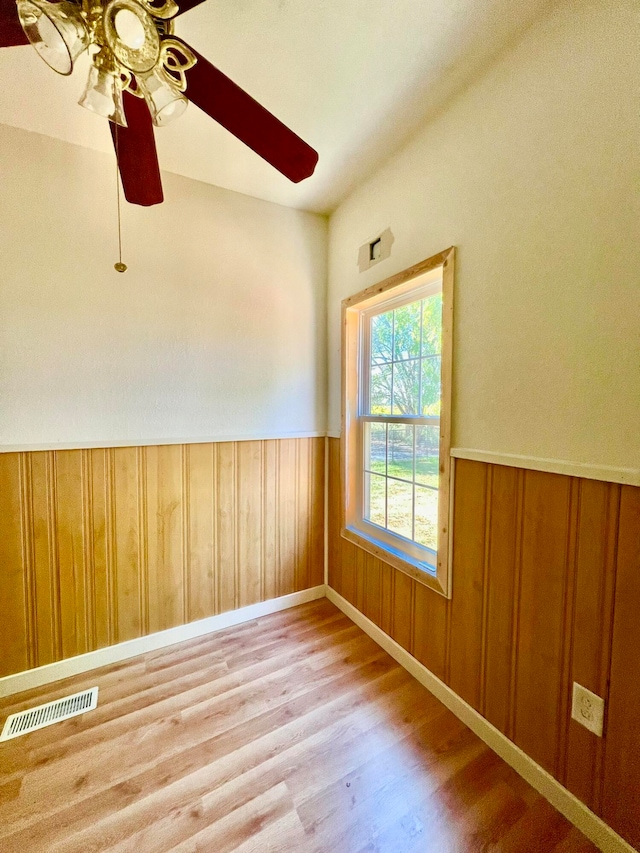 spare room with ceiling fan, wood walls, and hardwood / wood-style flooring