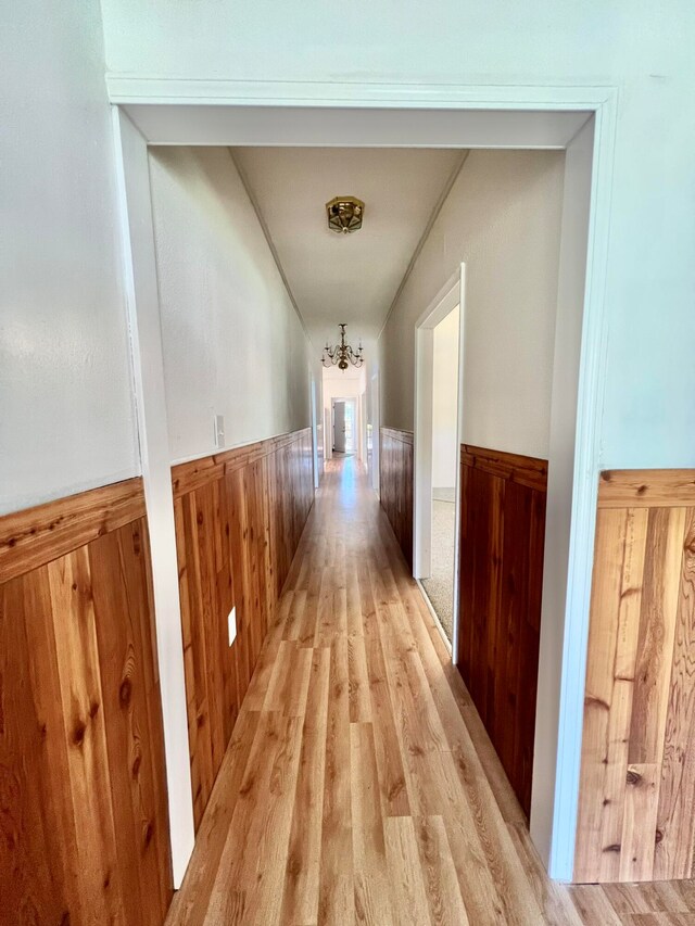 hall featuring light hardwood / wood-style flooring and wooden walls