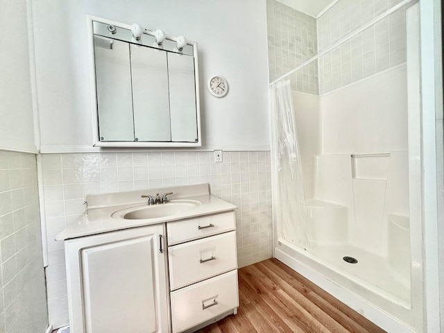 bathroom with a shower with shower curtain, wood-type flooring, tile walls, and vanity