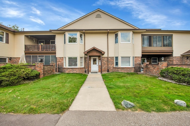 multi unit property with a front yard and brick siding