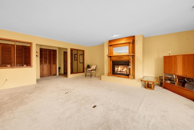 carpeted living room featuring visible vents and a large fireplace