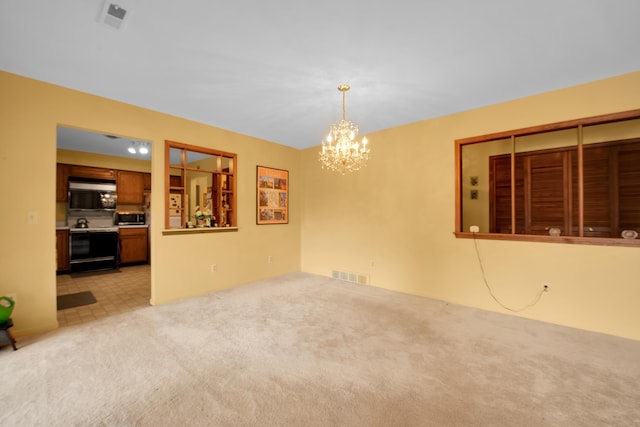 empty room featuring light colored carpet, visible vents, and a chandelier