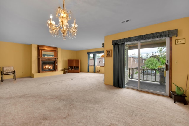 unfurnished living room featuring carpet flooring, visible vents, a chandelier, and a lit fireplace