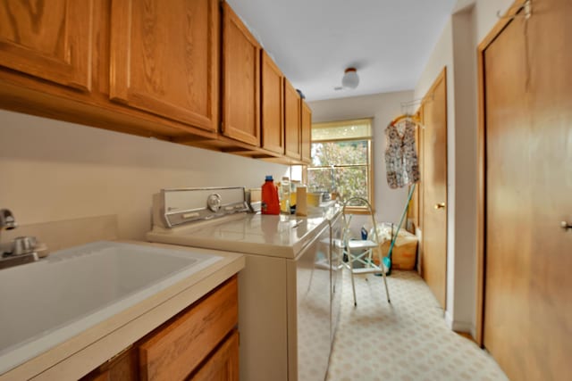 washroom featuring washing machine and clothes dryer, cabinet space, and a sink