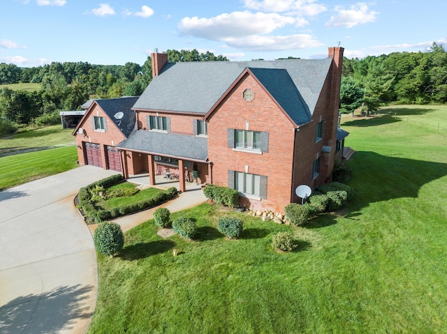 view of front of home featuring a front yard, concrete driveway, brick siding, and a chimney