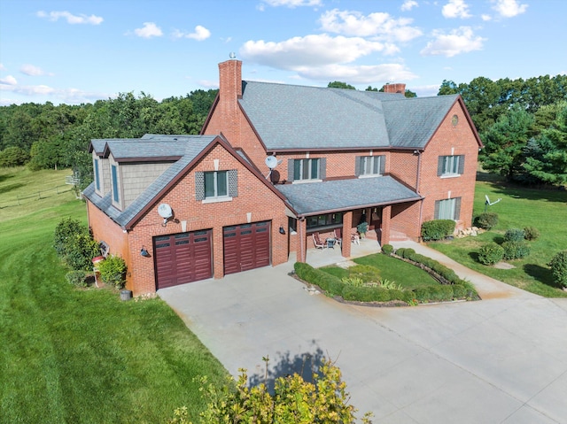 view of front of house featuring a porch, a chimney, a front lawn, concrete driveway, and brick siding