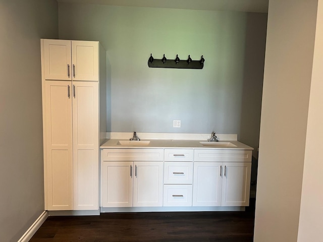 bathroom featuring double vanity, wood finished floors, baseboards, and a sink