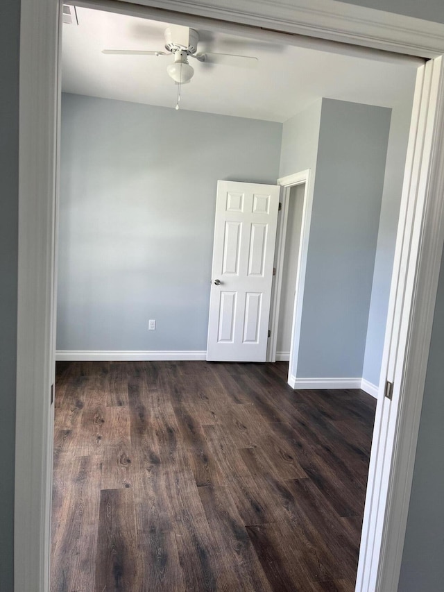 empty room featuring dark wood-style floors, baseboards, and ceiling fan