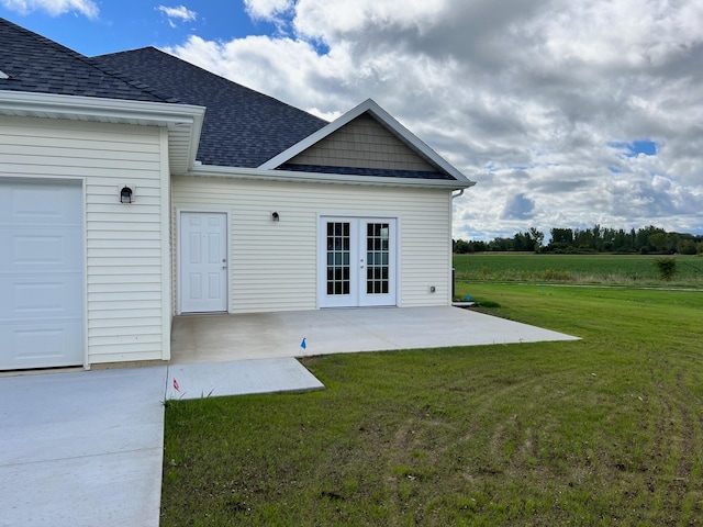 exterior space featuring a lawn, a garage, a patio, and french doors