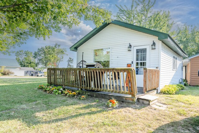 back of property with a deck and a lawn